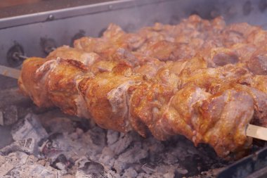 Delicious hot kebabs. Shish kebabs broils in barbecue. Smoke from hot coals. Meat are cooked on hot coals in barbecue, rotates on skewers for roasting clipart