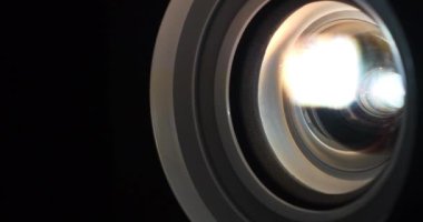 Çalışan projektör merceğine yakın çekim. Sinema salonu. Film projektörle gösterilir. Çalışan projektörlerin lensleri renk değiştirir. Farklı renklerin ışığı lenslerden geçer.