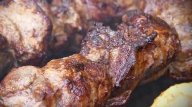 Barbeküde büyük şiş kebap. Yağlı, sağlıksız, kısmen yanmış kolesterollü et. Et, ızgarada sıcak kömürde pişirilir.