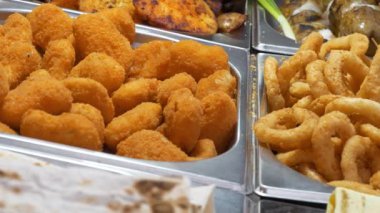 Fast food restoranında kaynatılmış, kızartılmış ve bol yağda kızartılmış çeşitli yemekler. Çeşitli şekillerde pişirilmiş patatesler. Patates kızartması, kızarmış patates.