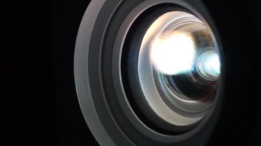 Projektör merceği yakın plan çalışıyor. Çalışan projektörlerin lensleri renk değiştirir. Sinema salonu. Film projektörle gösterilir. Farklı renklerin ışığı lenslerden geçer.