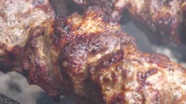 Barbeküde büyük, yağlı şiş kebap. Yağlı, sağlıksız, kısmen yanmış kolesterollü et. Et, ızgarada sıcak kömürde pişirilir.