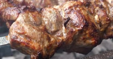 Büyük et parçalarıyla şiş kebap. Et, barbeküde sıcak kömürde pişirilir. Sıcak kömürden çıkan duman. Lezzetli sıcak kebap. Etten yağ damlaları