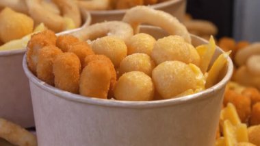 Kızarmış patates, kızarmış peynir topları ve büyük kağıt kaselerde diğer fırınlanmış yiyecekler.