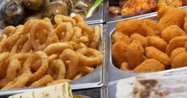 Fast food lokantasında kızartılmış ve kızartılmış çeşitli yiyecekler. Farklı şekillerde pişirilmiş patatesler, kızarmış patates, patates halkaları.