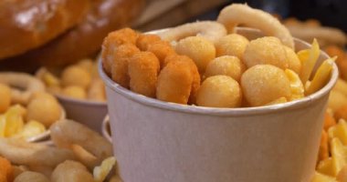 Kızarmış peynirli toplar, kızarmış patatesler ve büyük kağıt kaselerde diğer fırınlanmış yiyecekler.