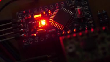 Karanlıkta yanan kırmızı LED ampullü elektronik devre. Elektronik bileşenleri güç kaynağına bağlı olan mikro devre. Mikro elektronik cihazlar, mikro devreler, rezistörler ve çipler