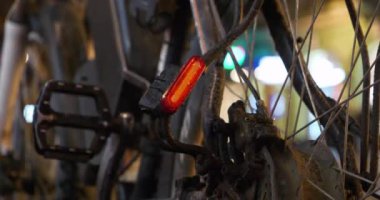 Bisiklette yanıp sönen kırmızı lamba, yol kenarında duran arabalar.