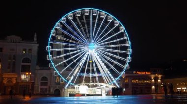 KYIV, UKRAINE, 25 Aralık 2023: İnsanlar Kyiv 'in tarihi Podil Mahallesi' ndeki Kontrat Meydanı veya Sözleşme Meydanı 'ndaki aydınlatmalarla birlikte akşam dönme dolaba yakın yürüyorlar