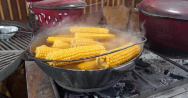 Kaynamış mısır, sıcak suyla birlikte büyük bir kazanda yatar. Ateş yakıyorum.