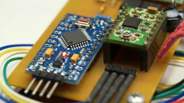 Elektronik bileşenleri güç kaynağına bağlı olan mikro devre. Elektronik tamir. Yanan kırmızı LED ampullü küçük bir elektronik devre. Mikrodevre, rezistanslar ve çipler