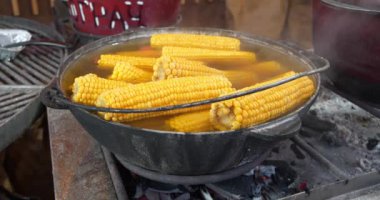 Kaynamış mısır, sıcak suyla birlikte büyük bir kazanda yatar. Ateş yakıyorum.
