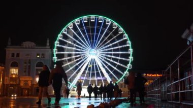 UKRAINE, KYIV, 25 ARALIK 2023: İnsanlar tarihi Podil Mahallesi 'nde Kyiv Meydanı veya Sözleşme Meydanı' ndaki aydınlatmalarla birlikte akşam dönme dolaba yakın yürür