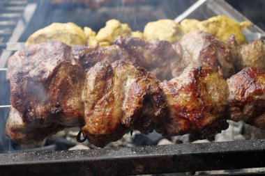 Meat on skewers. Large, fat kebabs are grilled on coals in a barbecue grill in a kebab shop clipart