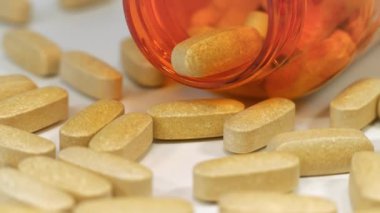 Masada büyük tabletler ve turuncu plastik kavanoz var. Farmakolojik biyokimya. Yüksek dozlar ve yan etkiler. Aşırı doz veya zehirlenme. İlaç maddesi, ilaç tedavisi, ilaçların verdiği hasar.