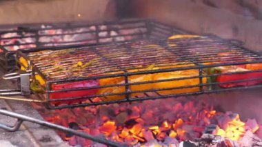 Biberler ızgarada sıcak kömürde pişirilir. Sarı ve kırmızı biberler barbeküde ızgara, kömür brazier. Aşçı ızgaraya mısır koydu.