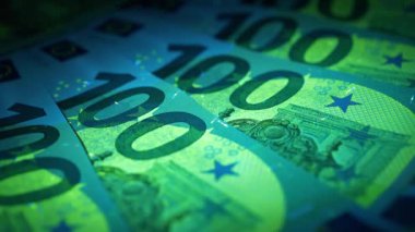 Avro banknotlarındaki güvenlik işaretleri ve unsurları ultraviyole ışık altında parlıyor. Yeşil ve mavi. UV ışığı altında 100 Euro.