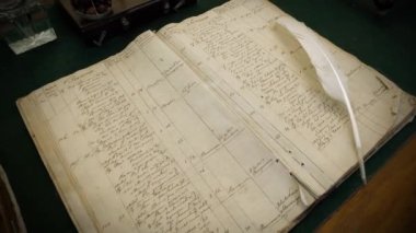 Masaya eski bir yemek tarifi kitabı ve yazmak için beyaz bir tüy kalem. 4K video eski moda sinema efektleri, eski çekim