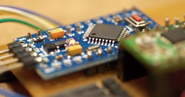 Elektronik bileşenleri güç kaynağına bağlı olan mikro devre. Elektronik tamir. Yanan kırmızı LED ampullü küçük bir elektronik devre. Mikrodevre, rezistanslar ve çipler