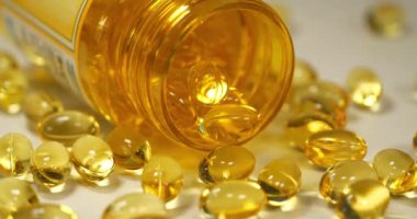 Omega-3 ve açık plastik kavanozlu sarı jel kapsüller. Sinema 4K 60fps video