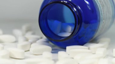 Farmakolojik biyokimya, ilaç tedavisi. İlaç maddesi, ilaç tedavisi. Masanın üzerinde beyaz tabletler ve mavi plastik kavanoz var. Zehirlenme ya da aşırı doz teması. Yüksek dozlar ve yan etkileri