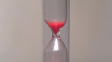 Kum saatindeki kırmızı kum. Zaman ters yönde, geriye doğru akar. Zaman sonsuz çöldeki kum gibidir, ama unutmayın, avuç içiniz kum saatinde. 4K 60fps makro çekim ters zaman videosu