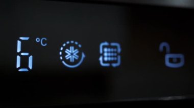 Mutfaktaki buzdolabının sıcaklığını ayarlıyorum. Buzdolabının dijital LCD ekranındaki sıcaklığı düşürüyorum. Sıcaklığı 6 dereceden 0 dereceye düşürüyorum.