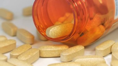 Masaya dağılmış sarı haplar ve turuncu kavanozu aç. Gerçekte bunlar 1 gramlık dozda C vitamini haplarıdır.