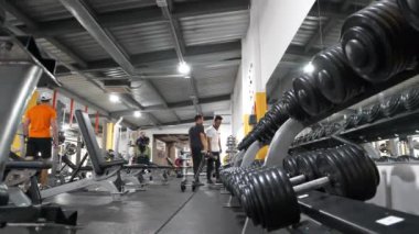 KYIV, UKRAINE, 2 Haziran 2023: Spor salonunda egzersiz yapan insanlar. Spor salonunda ağırlıkları farklı olan bir çift dambıl. Cesedi pompalamak için dambıllar.