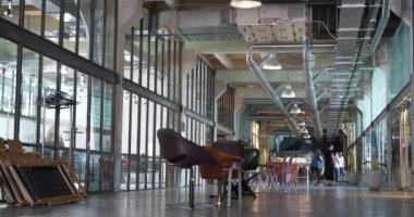 UKRAINE, IVANO-FRANKIVSK, 20 AĞUSTOS, 2022: Eski fabrika atölyesinde birlikte çalışan insanlar. Ortak çalışma - birçok şirketin işçilerinin ofis alanını paylaştığı bir düzenleme