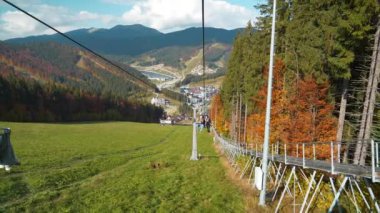 BUKOVEL, UKRAINE, OKTOBER 13, 2022: Bukovel 'de kayak asansöründeki insanlar - Karpat Dağları' ndaki köy ve en büyük kayak merkezi, Ukrayna 'nın İvano-Frankivsk Oblastı. UHD 4K Yavaş Hareket videosu