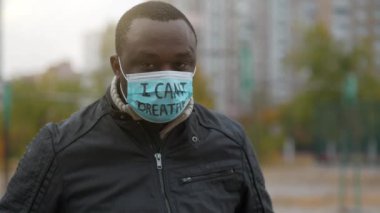 Tıbbi maskeli Afrikalı Amerikalı bir eylemci. Üstünde 