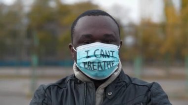 Tıbbi maskeli Afrikalı Amerikalı bir eylemci. Üzerinde 