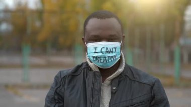 Tıbbi maskeli Afrikalı Amerikalı bir eylemci ve üzerinde 