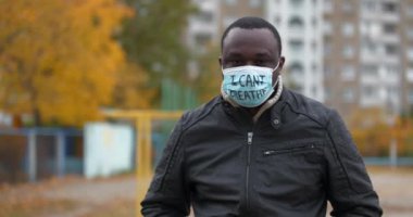 Tıbbi maskeli Afrikalı Amerikalı bir eylemci ve üzerinde 