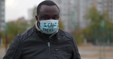 Tıbbi maskeli Afrikalı Amerikalı bir eylemci ve üzerinde 