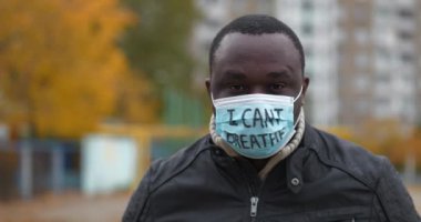 Tıbbi maskeli Afrikalı Amerikalı bir eylemci ve üzerinde 