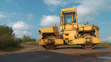Sarı yol pateni yeni yolda sıkışık asfalt. Yol silindiri - Toprak, çakıl, beton veya asfalt yapımında kullanılan sıkıştırıcı tipi mühendislik aracı