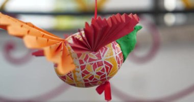 Plastikten, kağıttan ve boyalı Paskalya yumurtasından yapılmış bir kuş figürü ipe asılır ve döner.