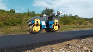 Yeni yolda asfalt sıkıştırılmış yol, tamamlanmış iş. Yol silindiri - Toprak, çakıl, beton veya asfalt yapımında kullanılan sıkıştırıcı tipi mühendislik aracı