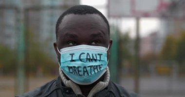 Tıbbi maskeli Afrikalı Amerikalı bir eylemci ve üzerinde 