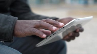 Slow Motion Afrikalı Amerikalı adam tablet bilgisayar kullanıyor. Siyah adamın elleri tablet bilgisayarı tutuyor, kapat. Tablet bilgisayarlı Afrikalı çalışmalar, sosyal ağlarda görüntülere göz atıyor