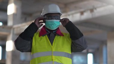 Yavaş hareket eden Afrikalı Amerikalı inşaatçı tıbbi koruyucu maske takıyor.