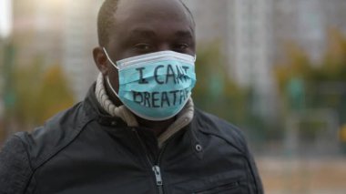 Tıbbi maskeli Afrikalı Amerikalı bir eylemci. Üstünde 