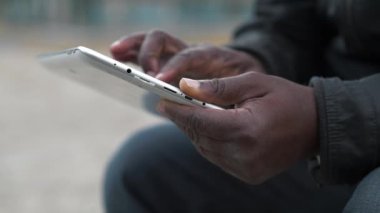 Afro-Amerikan erkek elleri tablet bilgisayarı tutuyor. Adam Tablet PC kullanır, sosyal ağlar üzerinden yayın yapar, eğik görünüm, yakın çekim