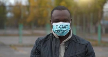 Tıbbi maskeli Afrikalı Amerikalı bir eylemci ve üzerinde 