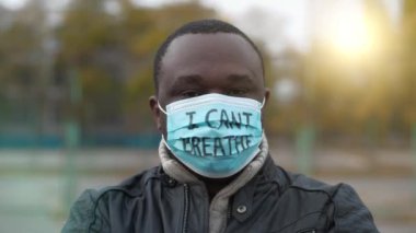 Tıbbi maskeli Afro-Amerikalı bir eylemci ve üzerinde 