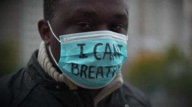 Tıbbi maskeli Afrikalı Amerikalı bir eylemci. Üstünde 