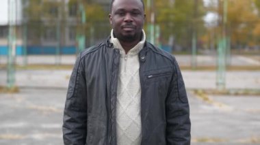 Nijeryalı Afrikalı Amerikalı bir adam spor sahasında duruyor kameraya bak ve gülümse.