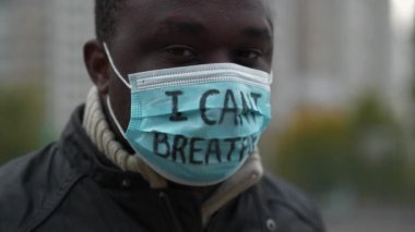 Tıbbi maskeli Afrikalı Amerikalı bir eylemci. Üstünde 